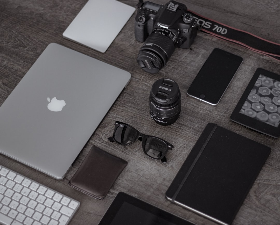 A collection of everyday tech gadgets and accessories on a desk, including a planner, smartphone, and wireless devices, showcasing an organized workspace.